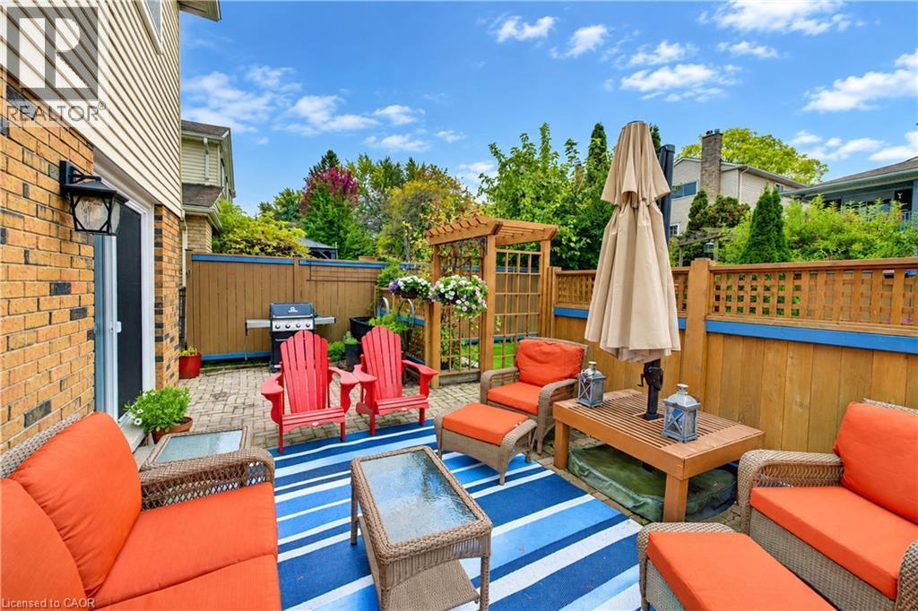 Brick exterior with attached outdoor lantern, sliding glass door, and a paver patio - 104 Deerwood Crescent, Kitchener, ON