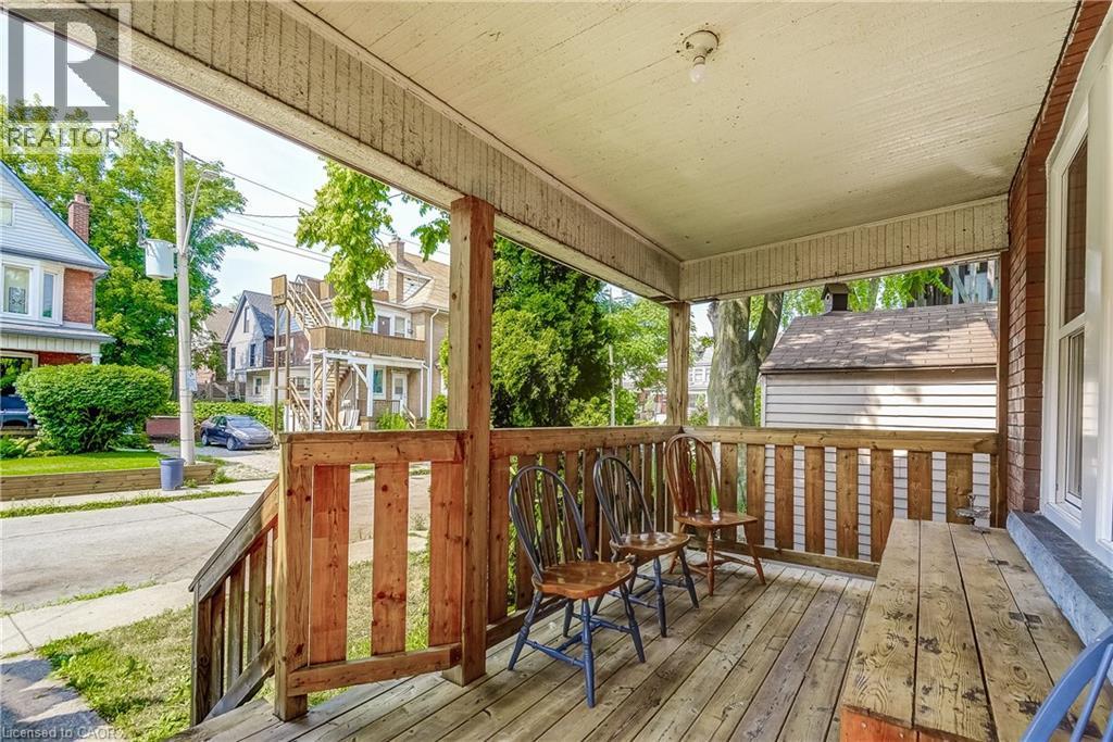 Covered front porch featuring wood-finish decking and railing - 11 Elm Street, Hamilton, ON