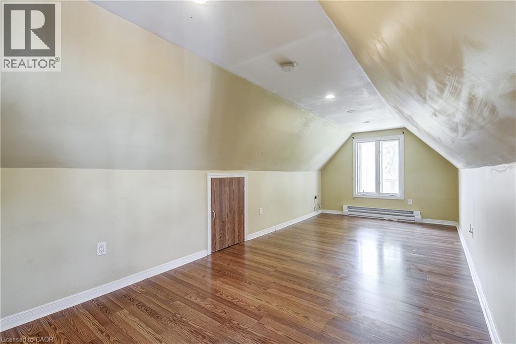 Sloped ceiling room featuring wood-finish flooring, a double window, and recessed lighting - 11 Elm Street, Hamilton, ON