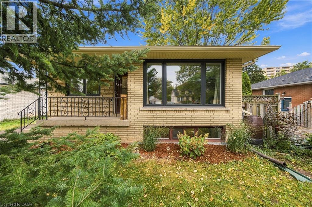 Light-colored brick exterior with dark-framed windows, a concrete front porch, and decorative wrought iron railings - 662 Dynes Road, Burlington, ON