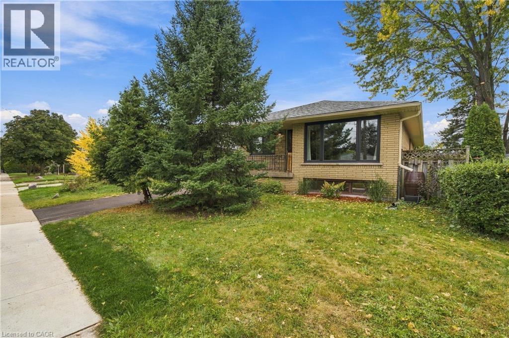 Brick exterior residence featuring a gabled roofline, mature trees, and a paved driveway - 662 Dynes Road, Burlington, ON