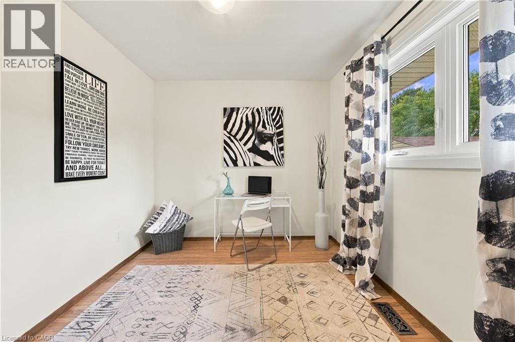 Wood-finish flooring with white baseboards, a single window, and a ceiling-mounted light fixture - 662 Dynes Road, Burlington, ON