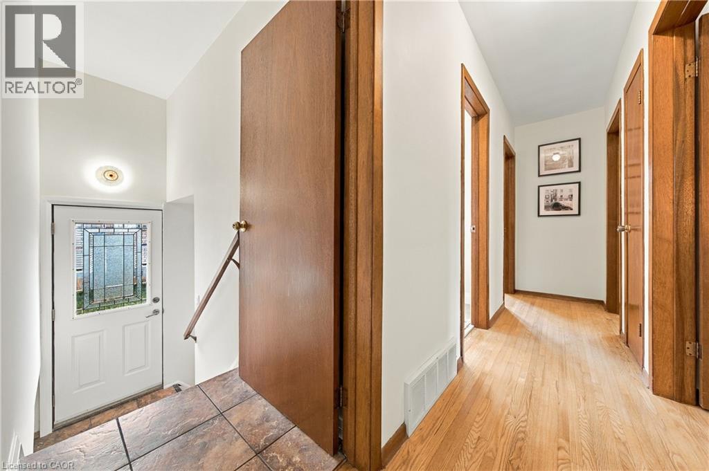 Entryway featuring a white door with decorative glass, tiled landing, and wood handrail - 662 Dynes Road, Burlington, ON