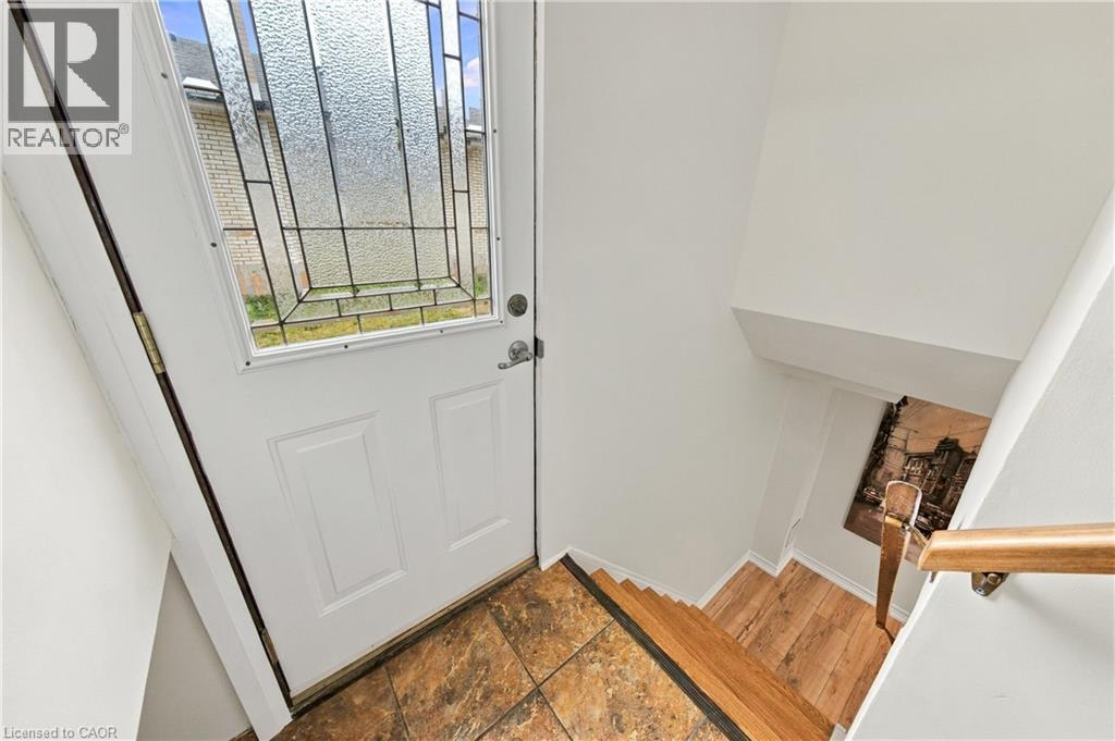 White entry door with decorative glass inserts, tile flooring at entry, wood-finish stairs, and wood handrail - 662 Dynes Road, Burlington, ON