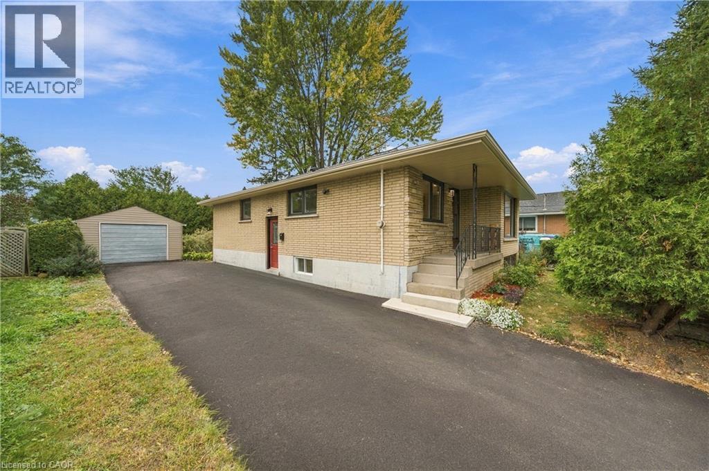 Brick exterior with stone accents, covered entry, front porch with railings, paved driveway, and detached garage - 662 Dynes Road, Burlington, ON