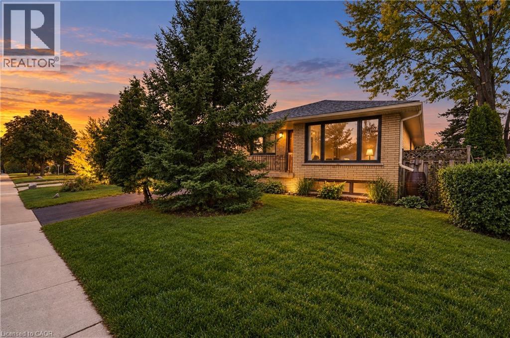 Brick exterior with a dark shingle roof, mature landscaping, and a paved driveway - 662 Dynes Road, Burlington, ON