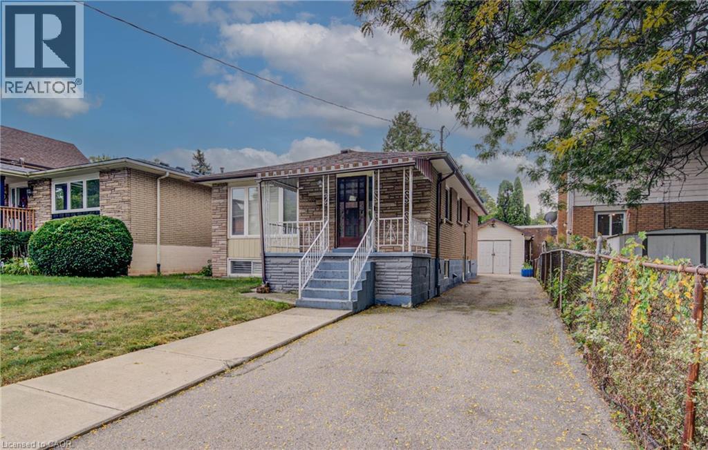 Brick and stone exterior with a covered porch, white railing, and concrete steps - 465 Herkimer Street, Hamilton, ON