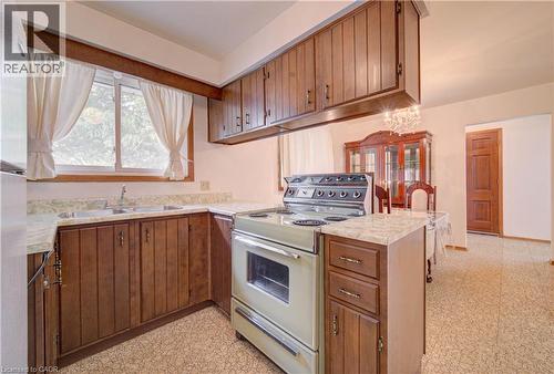 Kitchen featuring wood-finish cabinetry, light-colored countertops, a double basin sink, and a four-burner range - 465 Herkimer Street, Hamilton, ON 