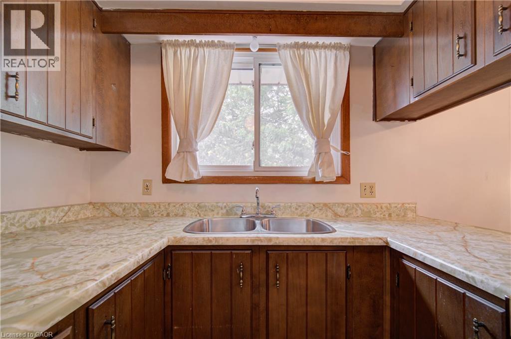 Wood-finish upper and lower cabinetry, white marbled countertops, and a double-basin stainless steel sink - 465 Herkimer Street, Hamilton, ON