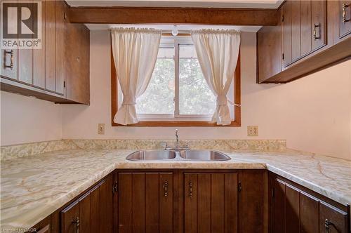 Wood-finish upper and lower cabinetry, white marbled countertops, and a double-basin stainless steel sink - 465 Herkimer Street, Hamilton, ON 