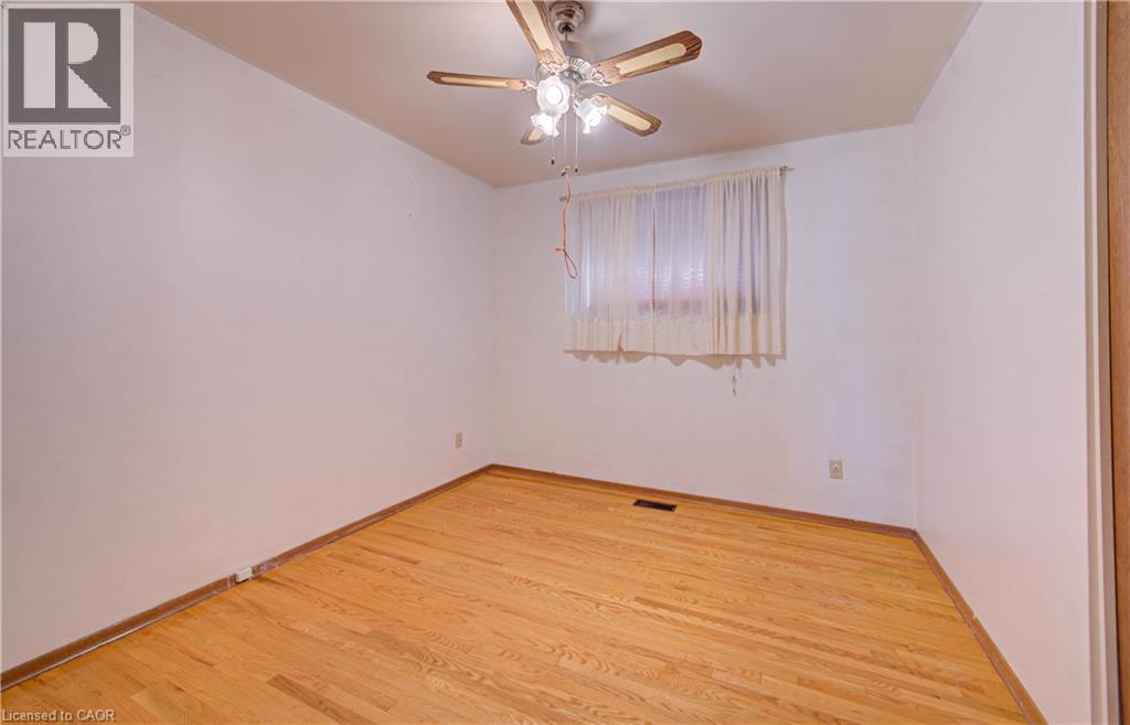Hardwood flooring, white painted walls, ceiling fan with integrated lighting, and window with privacy coverings - 465 Herkimer Street, Hamilton, ON