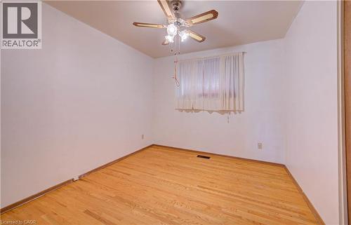 Hardwood flooring, white painted walls, ceiling fan with integrated lighting, and window with privacy coverings - 465 Herkimer Street, Hamilton, ON 