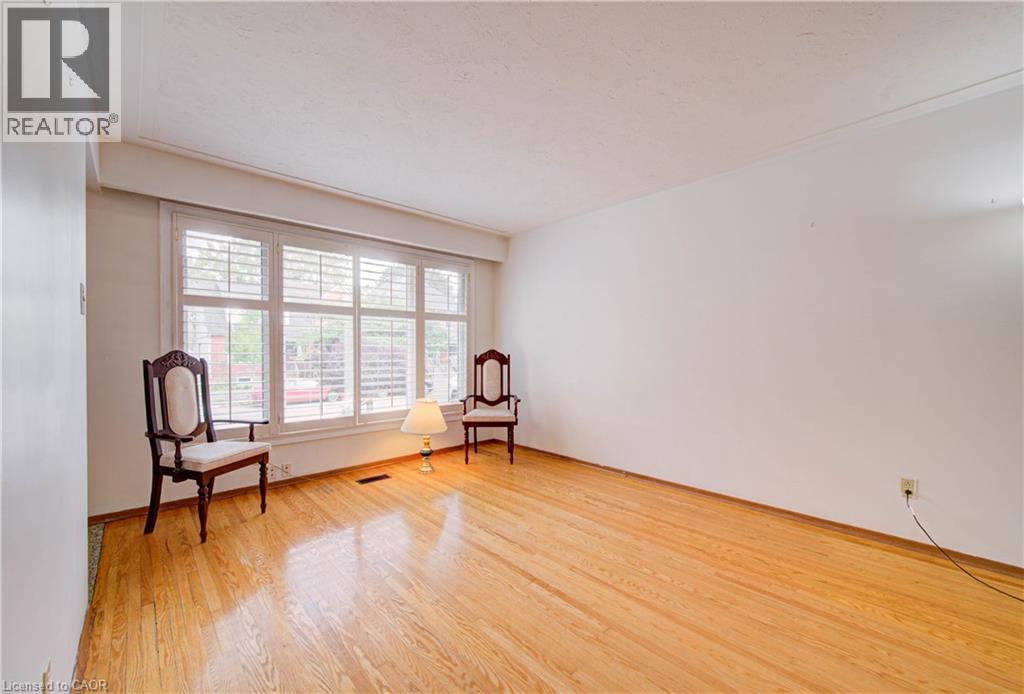 Hardwood flooring, white walls, and a large window with plantation shutters - 465 Herkimer Street, Hamilton, ON