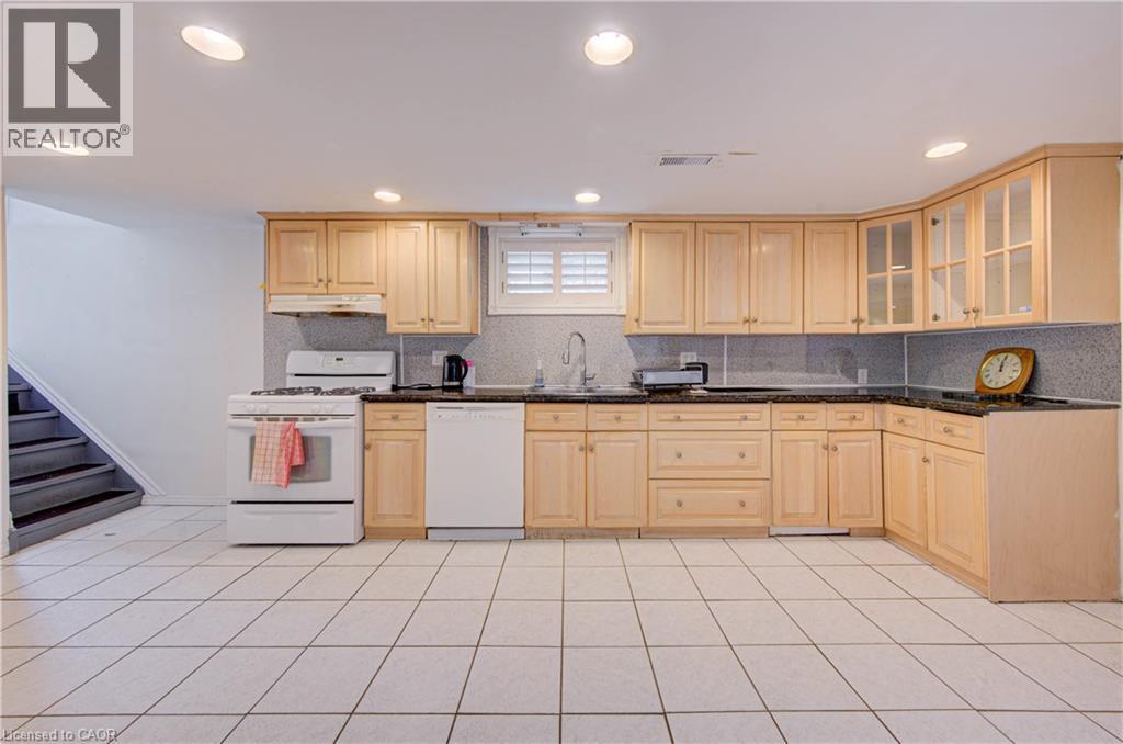 Full kitchen featuring wood-finish cabinetry, black countertops, and white tile flooring - 465 Herkimer Street, Hamilton, ON