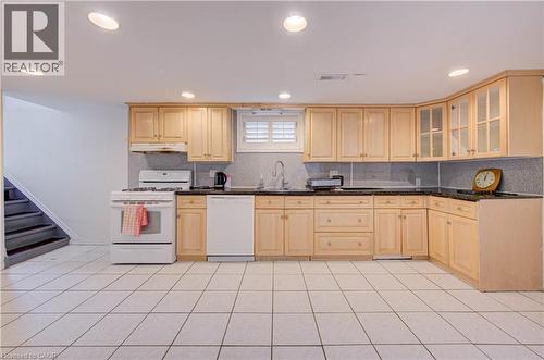 Full kitchen featuring wood-finish cabinetry, black countertops, and white tile flooring - 465 Herkimer Street, Hamilton, ON 