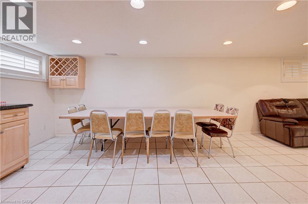 Recessed ceiling lighting, light wood-finish cabinetry with built-in wine rack, stone-finish countertop, white window shutters, and white tile flooring - 465 Herkimer Street, Hamilton, ON