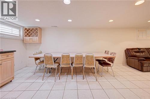 Recessed ceiling lighting, light wood-finish cabinetry with built-in wine rack, stone-finish countertop, white window shutters, and white tile flooring - 465 Herkimer Street, Hamilton, ON 