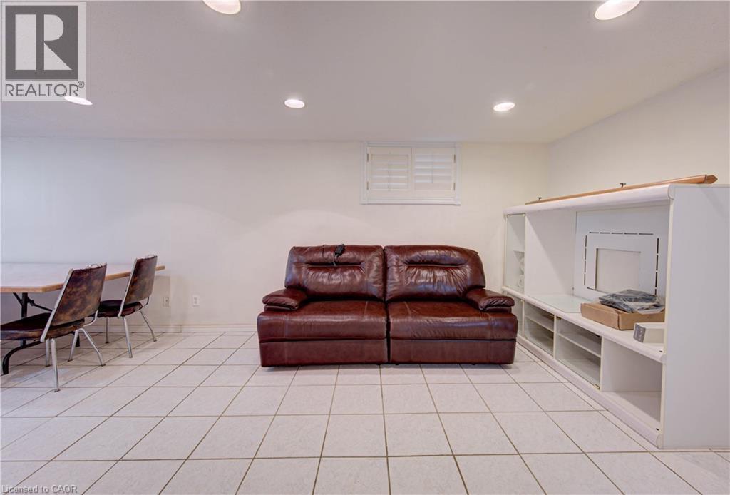 White tile flooring, recessed ceiling lighting, window with white plantation shutters, built-in shelving unit, and smooth white walls - 465 Herkimer Street, Hamilton, ON