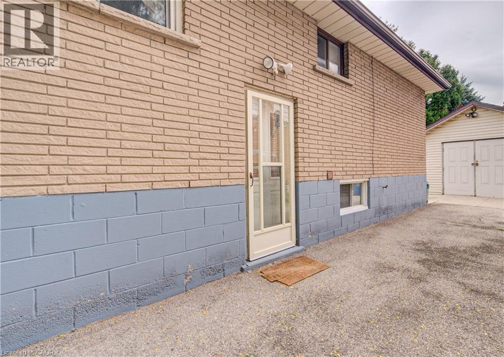 Brick exterior with a painted block foundation and a clear glass entry door - 465 Herkimer Street, Hamilton, ON