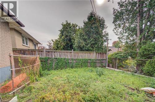 Rear yard featuring a wood privacy fence and mature perimeter trees - 465 Herkimer Street, Hamilton, ON 