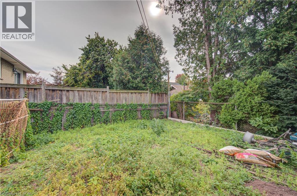 Expansive backyard with a wood privacy fence and mature perimeter trees - 465 Herkimer Street, Hamilton, ON