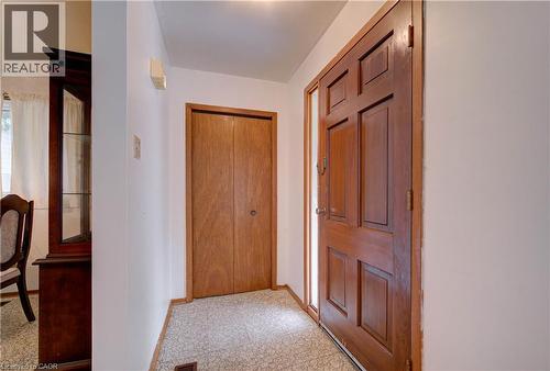 Paneled wood entry door with a sidelight, wood-finish bi-fold closet doors, and patterned tile flooring - 465 Herkimer Street, Hamilton, ON 