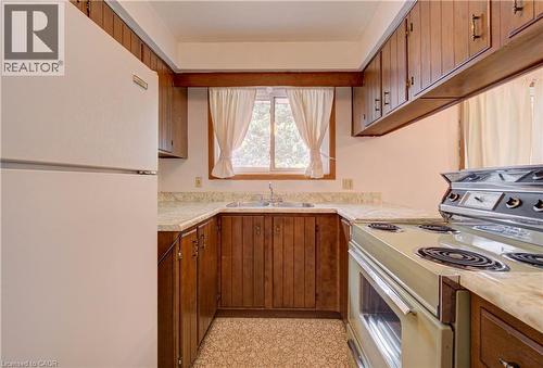U-shaped kitchen featuring wood cabinetry, stone-finish countertops, and a double basin sink - 465 Herkimer Street, Hamilton, ON 