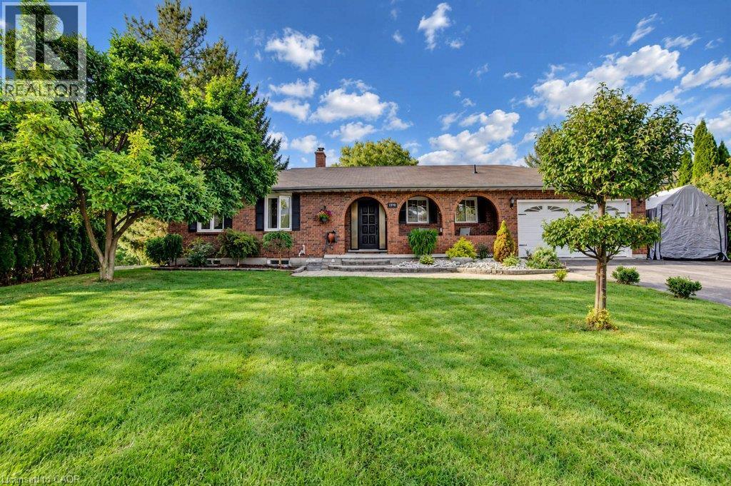 Brick exterior with arched entryway, attached garage, and mature landscaping - 1370 Thorman Place, Cambridge, ON