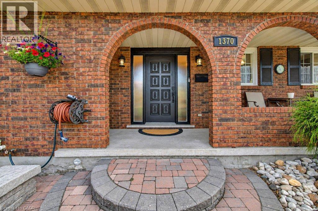 Brick exterior with arched entryways, a decorative front door with side lites, and a paver pathway - 1370 Thorman Place, Cambridge, ON