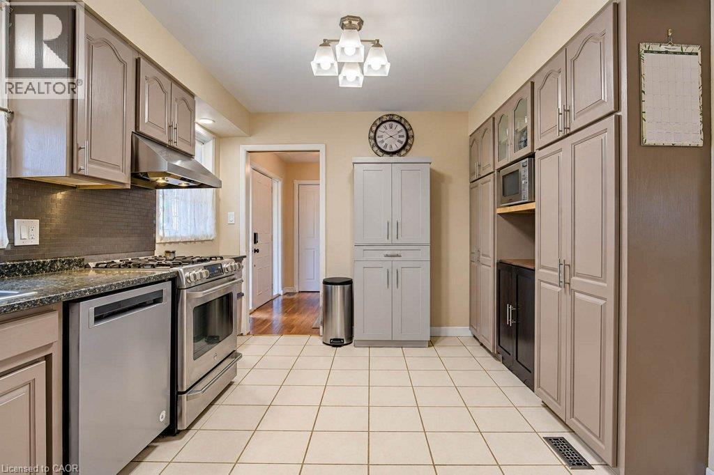 Kitchen featuring stainless steel appliances, grey cabinetry, dark speckled countertops, and a white tile floor - 1370 Thorman Place, Cambridge, ON