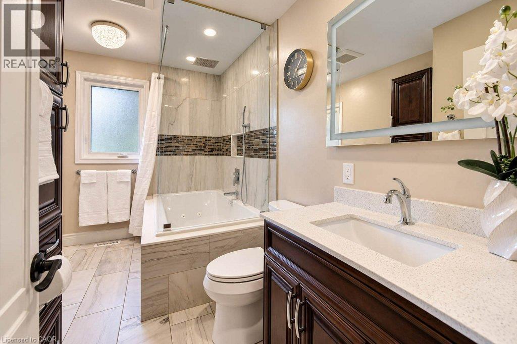 Walk-in shower with glass enclosure, built-in bathtub, wood-finish vanity with countertop, and large framed mirror - 1370 Thorman Place, Cambridge, ON