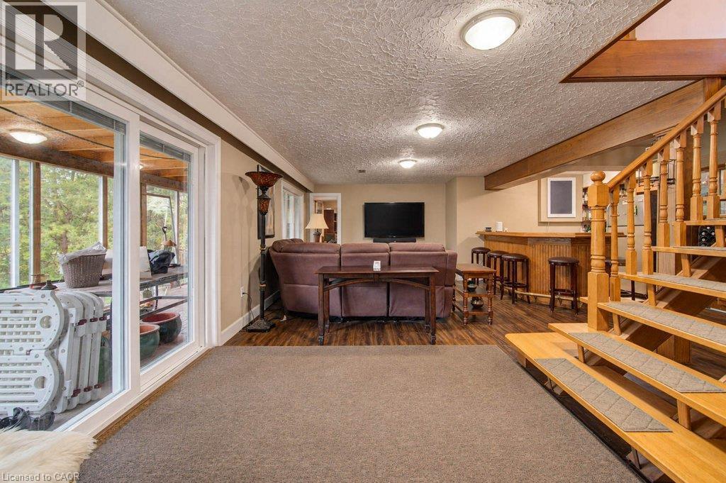 Full finished lower level with a built-in bar, wood-finish flooring, and direct access to an enclosed porch - 1370 Thorman Place, Cambridge, ON