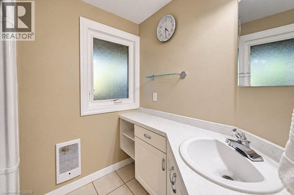 White window trim, an integrated sink basin, a wall-mounted glass shelf, and cabinet storage with brushed nickel hardware - 1370 Thorman Place, Cambridge, ON