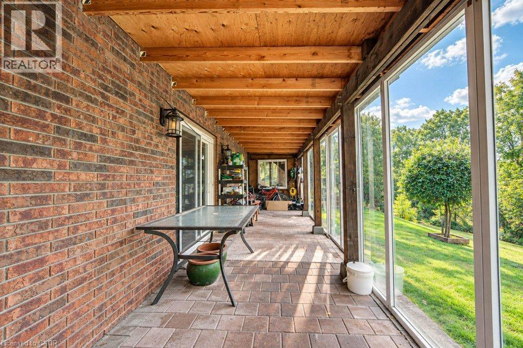 Enclosed brick-clad patio featuring a wood-beam ceiling, paver flooring, and floor-to-ceiling windows - 1370 Thorman Place, Cambridge, ON