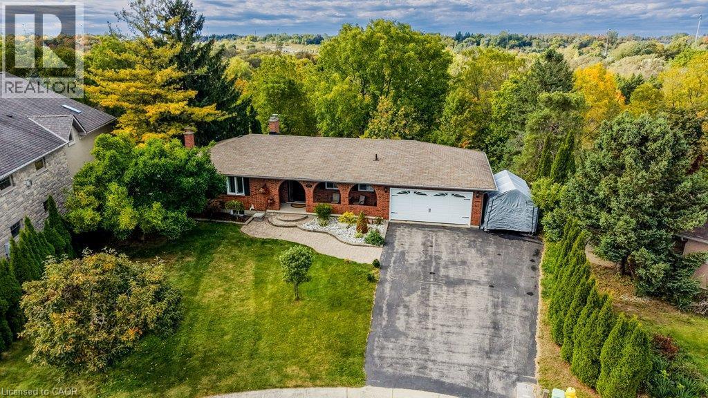 Brick exterior with white garage door, asphalt driveway, and mature landscaping - 1370 Thorman Place, Cambridge, ON