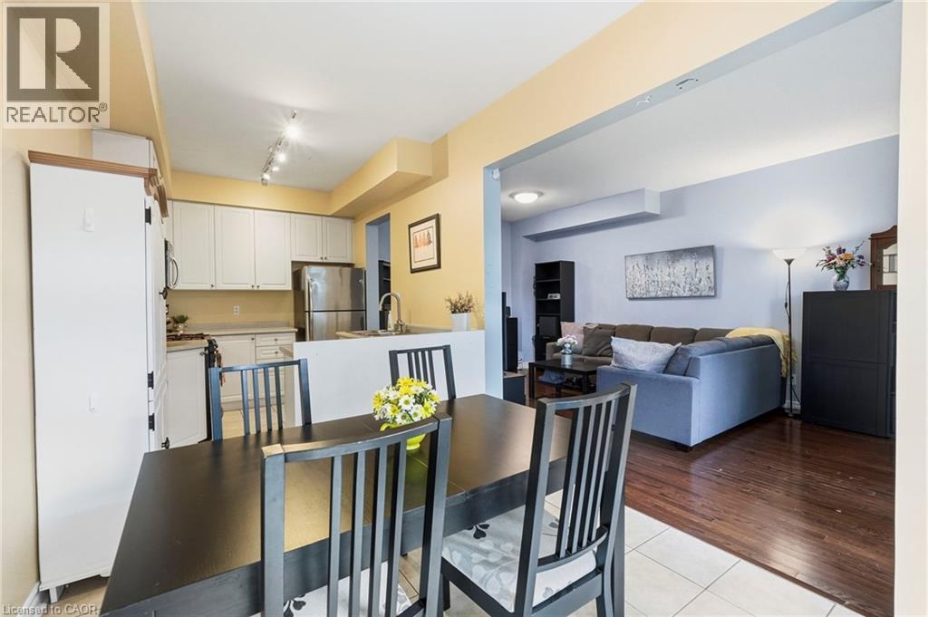 Open-concept dining area with tile flooring and a kitchen featuring white cabinetry and stainless steel appliances - 1076 Ryckman Common, Burlington, ON