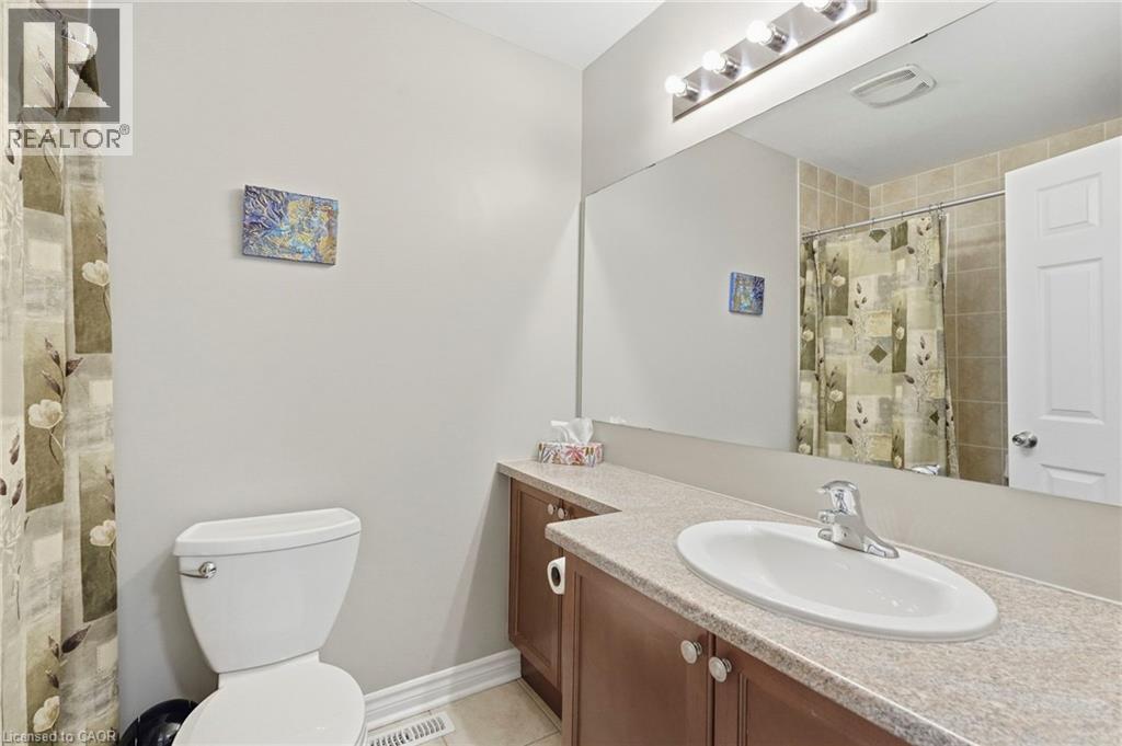 Bathroom featuring a vanity with a laminate countertop, integrated sink, and wood-finish cabinetry - 1076 Ryckman Common, Burlington, ON