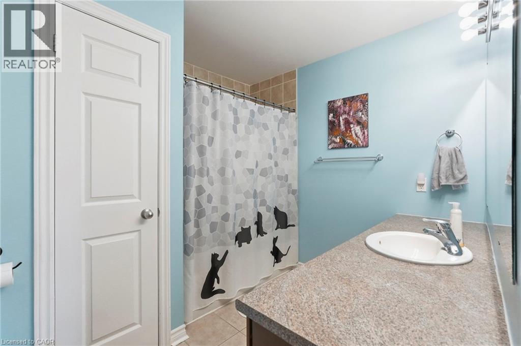 Bathroom featuring a vanity with an integrated sink, a chrome faucet, and a shower with tiled surround - 1076 Ryckman Common, Burlington, ON