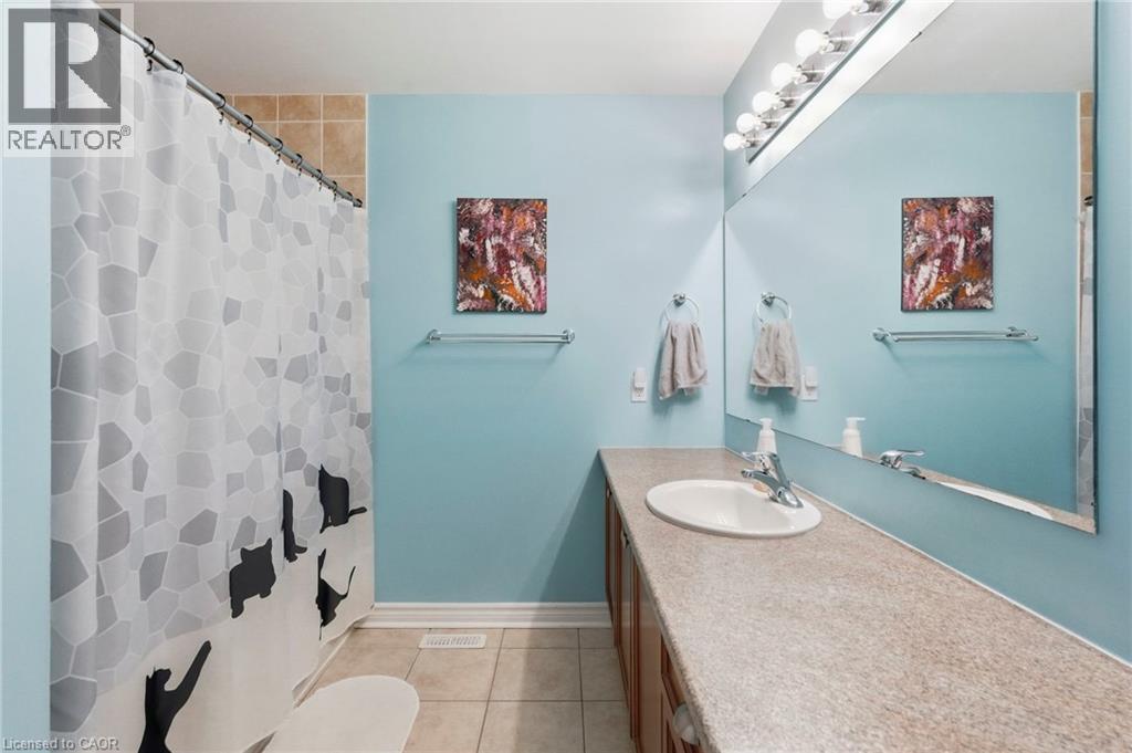 Bathroom featuring a single basin vanity, integrated mirror, multi-bulb vanity lighting, and tiled flooring - 1076 Ryckman Common, Burlington, ON