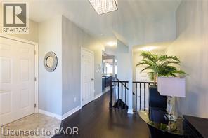 Entryway featuring wood-finish flooring, two-panel doors, and a decorative ceiling light fixture - 28 Madonna Drive, Hamilton, ON