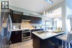 Kitchen featuring stainless steel appliances, dark wood-finish cabinetry, a white countertop, and a tile backsplash - 28 Madonna Drive, Hamilton, ON
