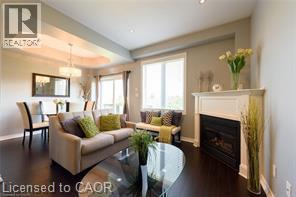 Dark wood-finish flooring, tray ceiling with recessed lighting, fireplace with mantel, and large window - 28 Madonna Drive, Hamilton, ON