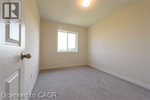 Carpet flooring, neutral wall paint, a single window, and a ceiling-mounted light fixture - 28 Madonna Drive, Hamilton, ON