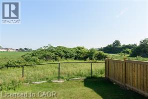 Expansive grassy area featuring a black metal fence and a wood plank fence - 28 Madonna Drive, Hamilton, ON