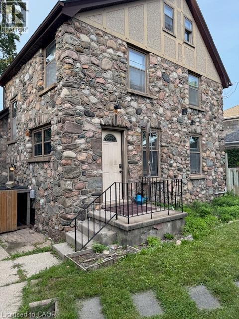Stone facade exterior with an arched entryway, gabled roofline, and multiple windows - 255 Main Street, Cambridge, ON