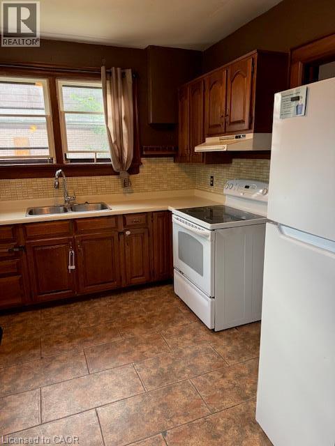 Kitchen featuring wood-finish cabinetry, tile backsplash, laminate countertops, and tile flooring - 255 Main Street, Cambridge, ON