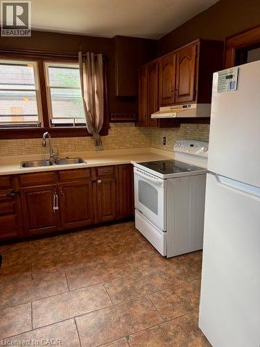 Kitchen featuring wood-finish cabinetry, tile backsplash, laminate countertops, and tile flooring - 255 Main Street, Cambridge, ON 