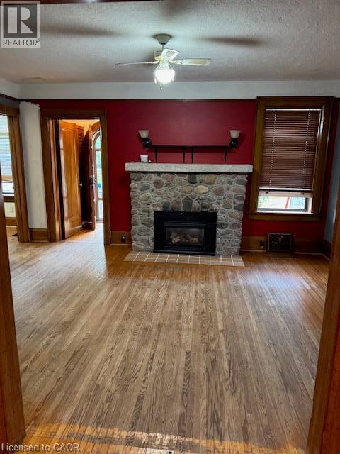 Hardwood flooring, stone-clad fireplace, ceiling fan with light fixture, wood-framed entryways, and window with blinds - 255 Main Street, Cambridge, ON