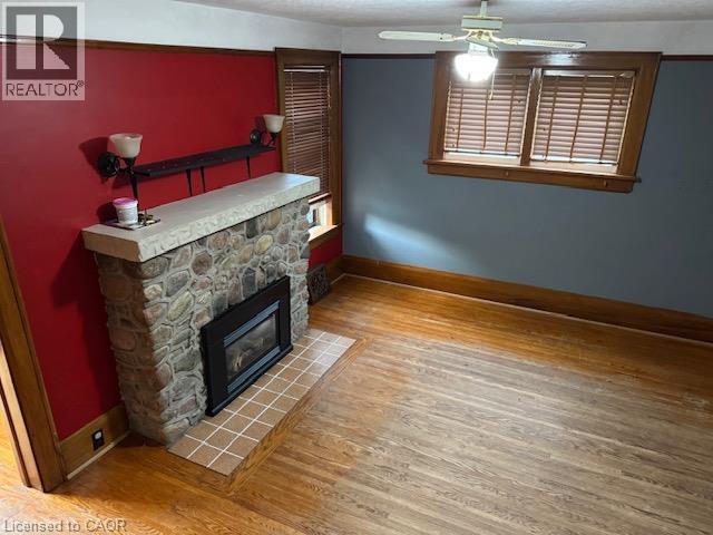Stone-clad fireplace with a hearth, wood-finish flooring, and built-in ceiling fan with lighting - 255 Main Street, Cambridge, ON