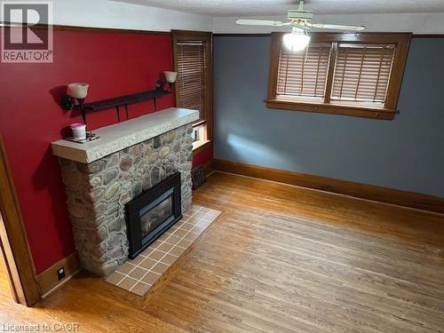 Stone-clad fireplace with a hearth, wood-finish flooring, and built-in ceiling fan with lighting - 255 Main Street, Cambridge, ON 